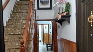 Un escalier menant à un palier agrémenté d’une rambarde en bois, d’un tableau encadré au mur et d’une petite étagère sur laquelle est posée une plante.