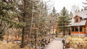 A wooden bridge leading to a lodge surrounded by trees.