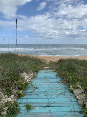 Un sendero que lleva a una playa, con el océano al fondo.