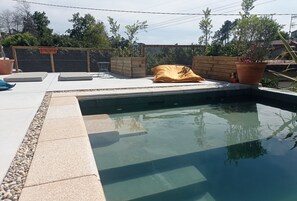 A swimming pool with a wooden deck, a yellow cushion, and a potted plant. - House with pool of 14 m ecological (Porriño)