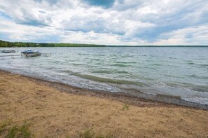 A beach with a dock and calm water.