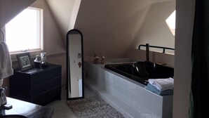 Un baño moderno con una bañera independiente, un tocador con espejo y un ventanal que proporciona luz natural.