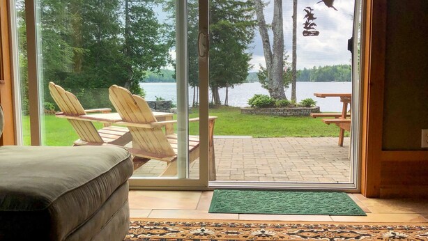 Une chambre avec vue sur un lac, un espace extérieur aménagé pour s’asseoir et une porte donnant sur l’extérieur.