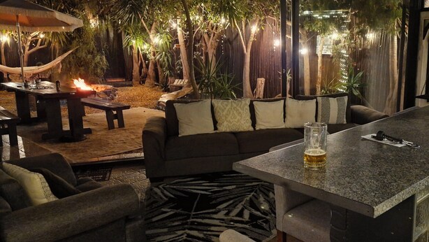 An outdoor seating area with a fire pit, a sofa, and a bar table.