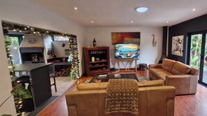 A modern living room with a sofa, a coffee table, a fireplace, and a large window with a view of the outdoors.