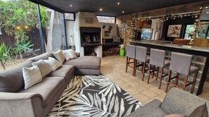 A cozy outdoor seating area with a sofa, bar stools, and a grill.