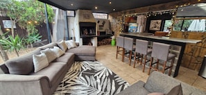 A cozy outdoor seating area with a sofa, bar stools, and a grill.