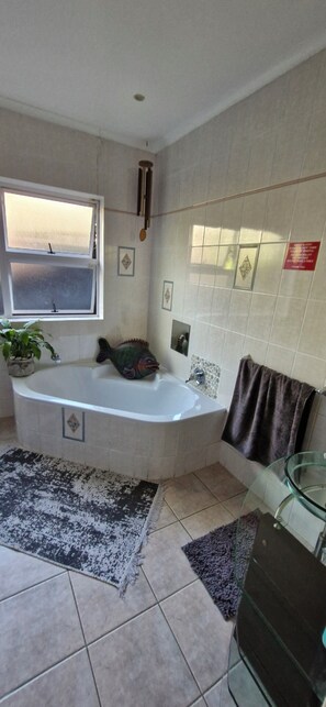 Un baño con bañera, ventana, toallero y cabina de ducha de vidrio.