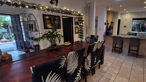 A modern kitchen with a bar area, a dining space with patterned chairs, and a view of the outdoors.