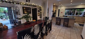 A modern kitchen with a bar area, a dining space with patterned chairs, and a view of the outdoors.