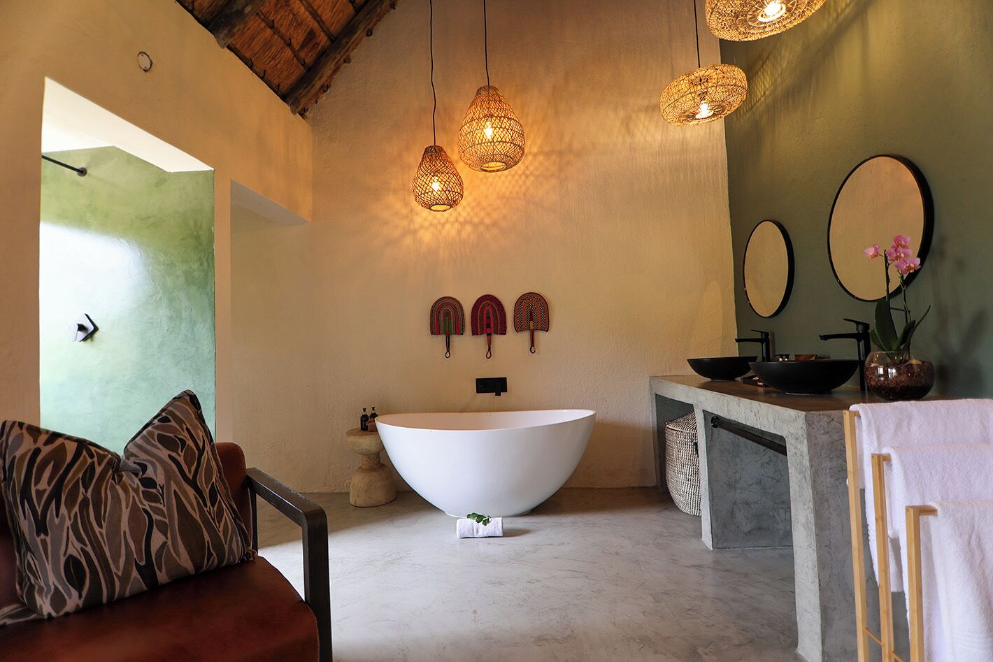 Un baño moderno con una bañera independiente, un mueble de tocador de madera y un espejo grande.