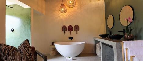 Un baño moderno con una bañera independiente, un mueble de tocador de madera y un espejo grande.