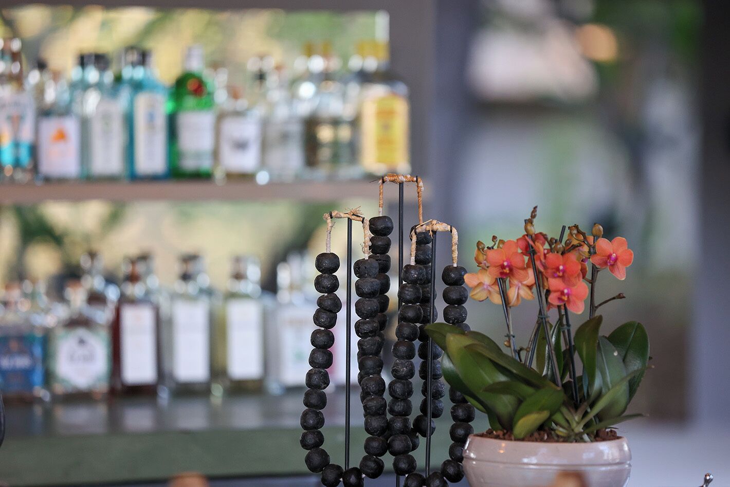 A bar area with a display of black beads and a potted plant with orange flowers.