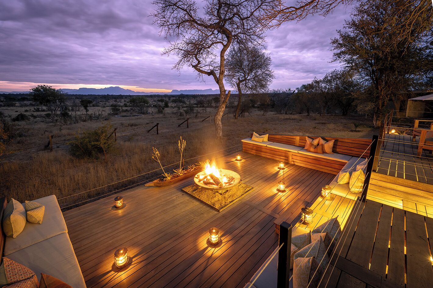 Eine Terrasse mit Feuerstelle, Sitzgelegenheiten und Kerzen.