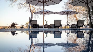 Una piscina al aire libre, sombrillas, sillones reclinables de piscina