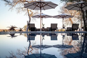 Una piscina al aire libre, sombrillas, tumbonas