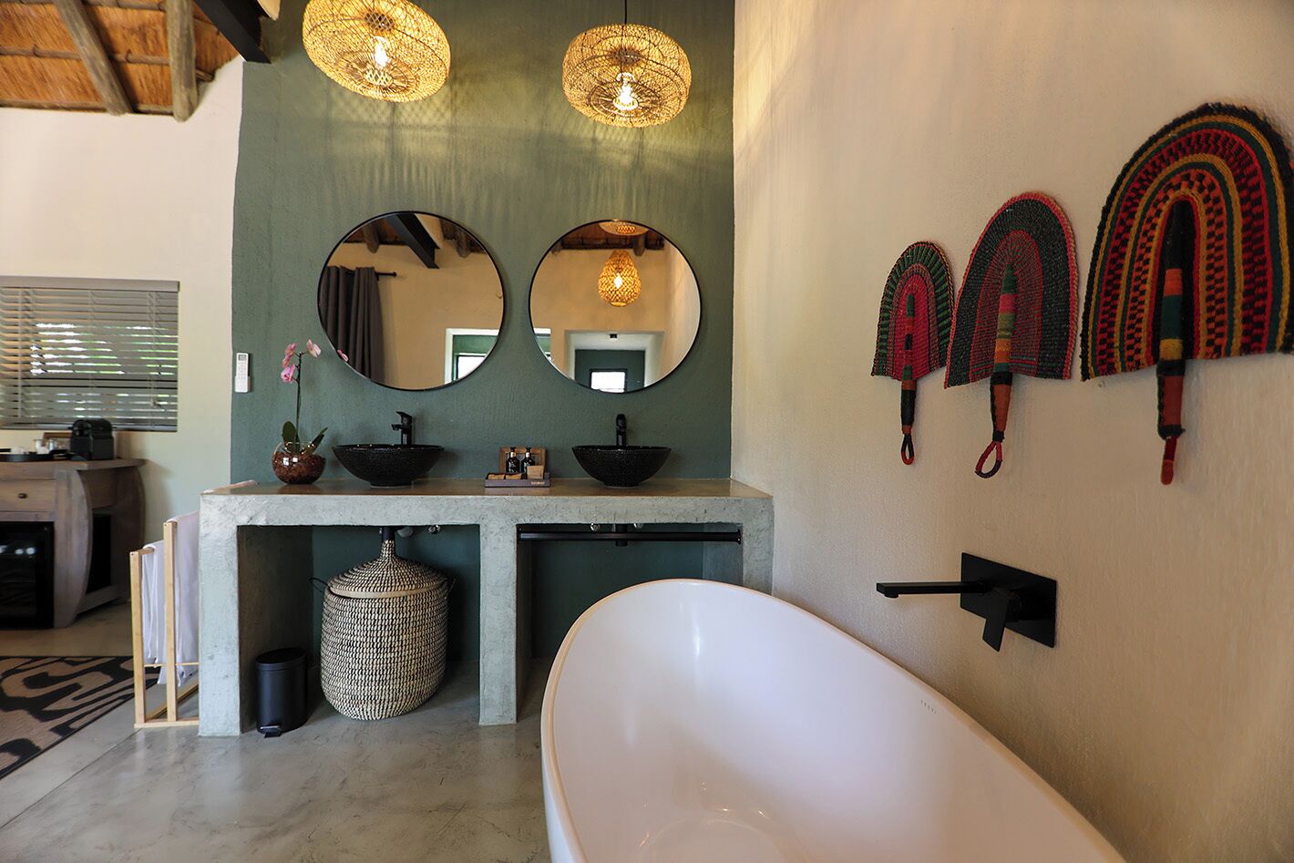 A modern bathroom with a freestanding bathtub, a vanity with two sinks, and decorative wall mirrors.