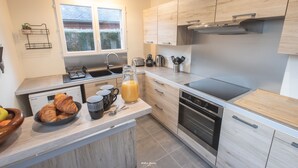 A modern kitchen with wooden cabinets, a built-in oven, a sink, and a window.