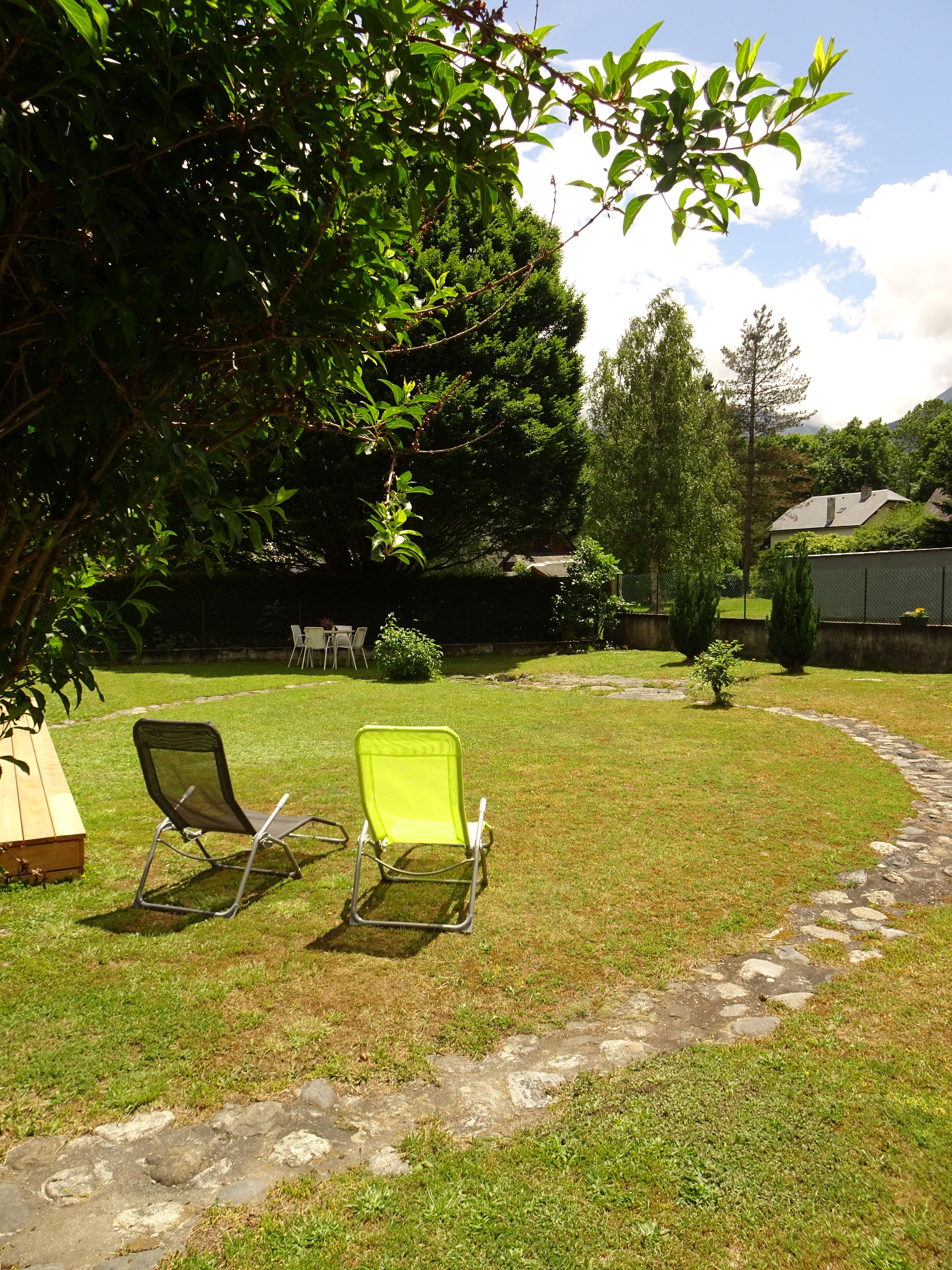 Ein Garten mit zwei Liegestühlen, einem Kiesweg und einer Holzterrasse.
