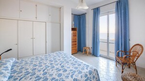 Un dormitorio con cama, armario y una silla.