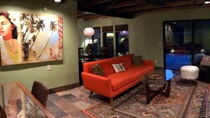A living room with a red sofa, a glass coffee table, and a patterned rug. - The Polynesian- 2 miles to Siesta Beach, Heated Pool, Furry Friends Stay Free (Sarasota)