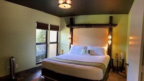 A bedroom with a large bed, a standing heater, a window, and a small table with a plant. - The Polynesian- 2 miles to Siesta Beach, Heated Pool, Furry Friends Stay Free (Sarasota)