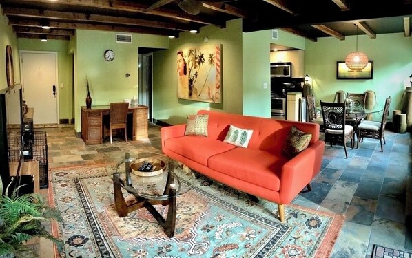 Uma sala de estar aconchegante com um sofá vermelho, tapetes estampados e uma mesa de centro.