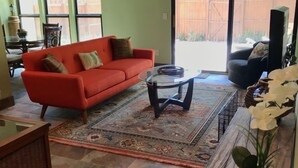A living room with a red sofa, a glass coffee table, and a patterned rug. - The Polynesian- 2 miles to Siesta Beach, Heated Pool, Furry Friends Stay Free (Sarasota)