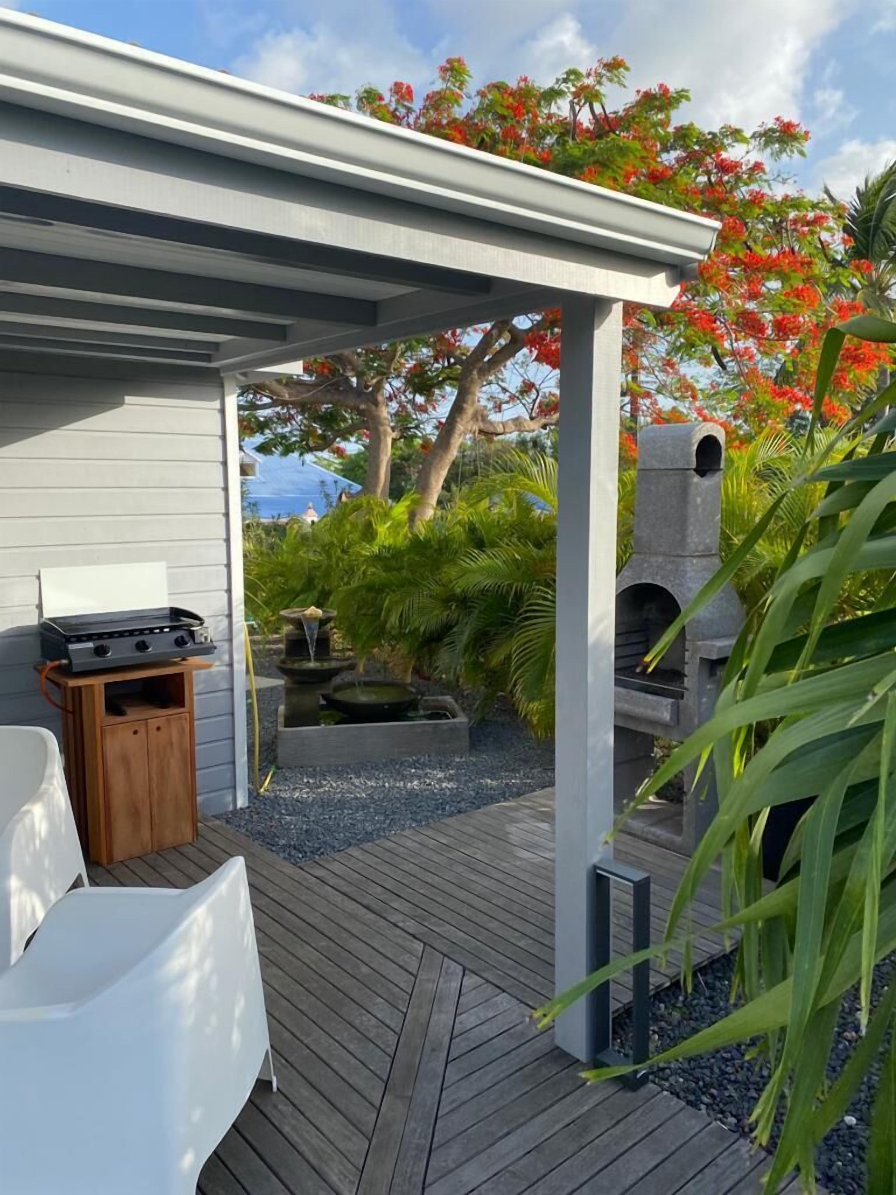A covered outdoor area with a grill, seating, and a small water feature.
