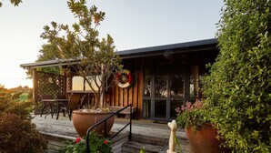 A modern outdoor seating area with a wooden deck, a large planter with flowers, and a welcoming entrance with a 'Welcome' sign. - Barnacle Bills (Kaikoura)