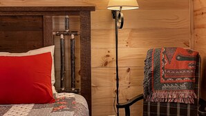 Een houten kamer met een bed, een lamp en een stoel.