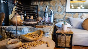 A rustic kitchen with stone walls, wooden bowls filled with nuts, a coffee machine, and a cozy seating area with cushions. - Pet friendly home in Zagrad (Zagrad)
