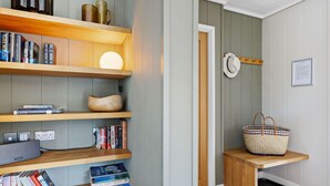 Ett rum med en bokhylla, en lampa, en korg och en dörr.