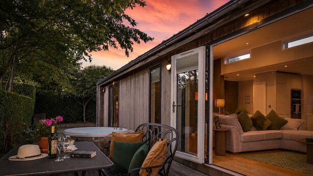 Ett modernt hus med en uteplats, ett bubbelbad och ett mysigt vardagsrum med en soffa och kuddar.