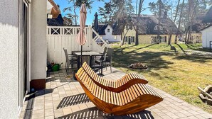 Une terrasse avec un banc en bois, une table et des chaises.