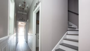 A hallway with a staircase, white walls, and a chandelier. - Mid City Mansion, Southern Living Walk to streetcar (New Orleans)