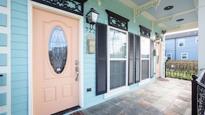 A house with a peach-colored front door, black shutters, and a stone-paved porch. - Mid City Mansion, Southern Living Walk to streetcar (New Orleans)