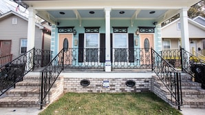 A two-story house with a covered porch, a brick foundation, and a black metal railing. - Mid City Mansion, Southern Living Walk to streetcar (New Orleans)