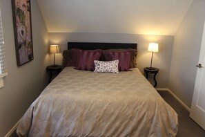 A neatly made bed with a patterned bedspread, two bedside lamps, and a headboard.