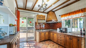 Een keuken met houten kastjes, een inbouwoven en een raam met gordijnen.