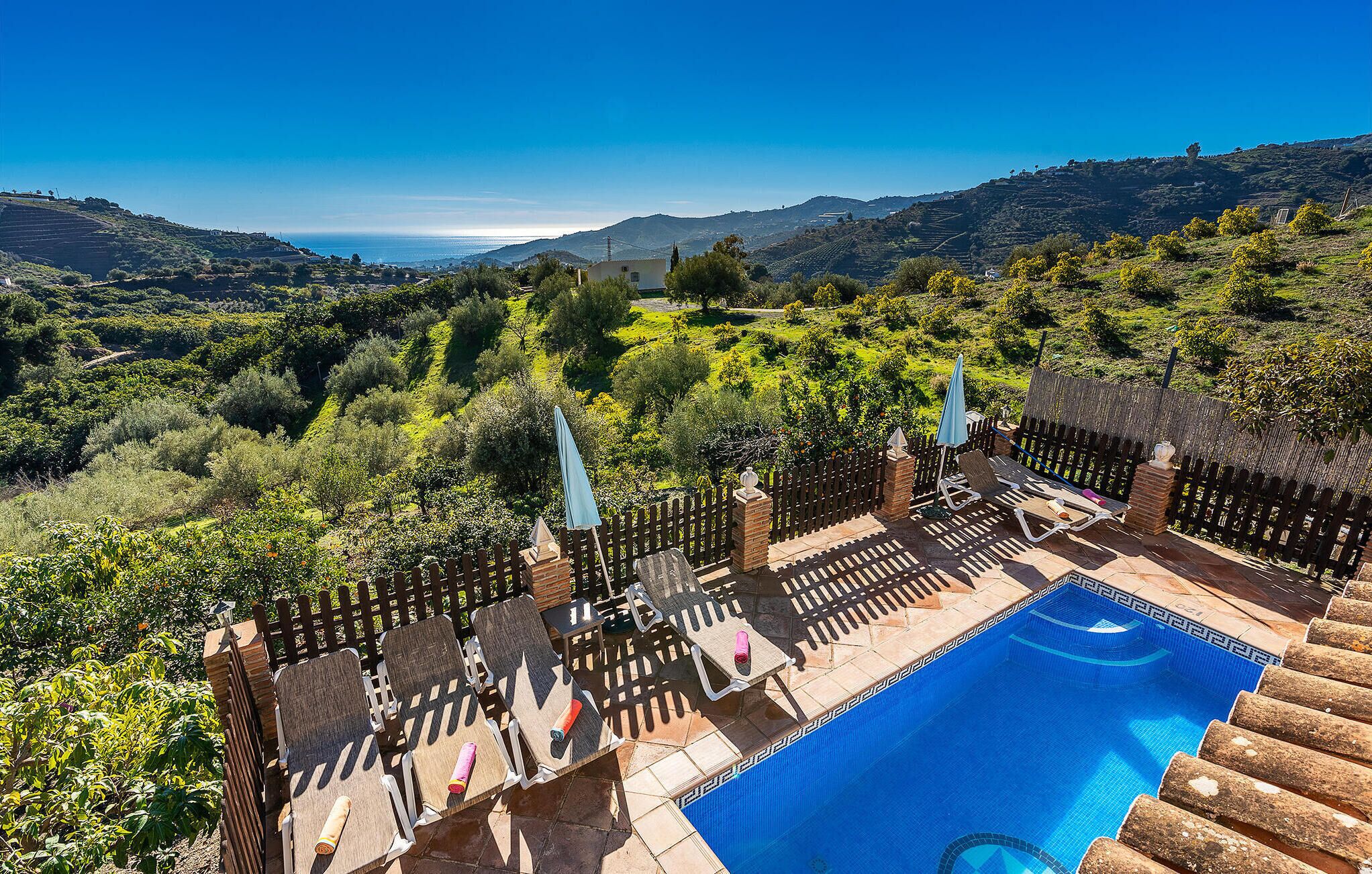 Zona de piscina con sillones de descanso y vistas a un paisaje montañoso.