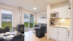 Un espacio habitable compacto con kitchenette, un comedor con mesa para dos personas y una zona de estar con sofá y sillones.