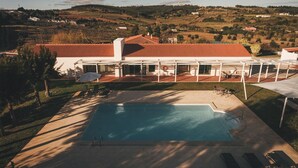 Un área de piscina con sillones de descanso y un porche cubierto.