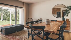 Un comedor con una mesa de madera, sillas negras y un espejo grande en la pared.