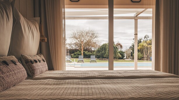 Un dormitorio con una cama grande, vistas a una piscina y un patio.
