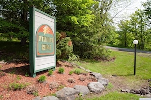 A sign for Windham Ridge with a logo, surrounded by a landscaped area with rocks and shrubs.