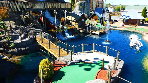 A water park with a wooden bridge, a large yellow airplane, and a water slide.
