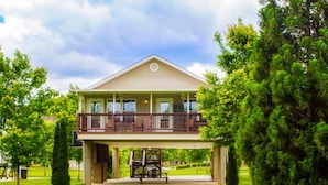 A two-story house with a balcony, surrounded by greenery.