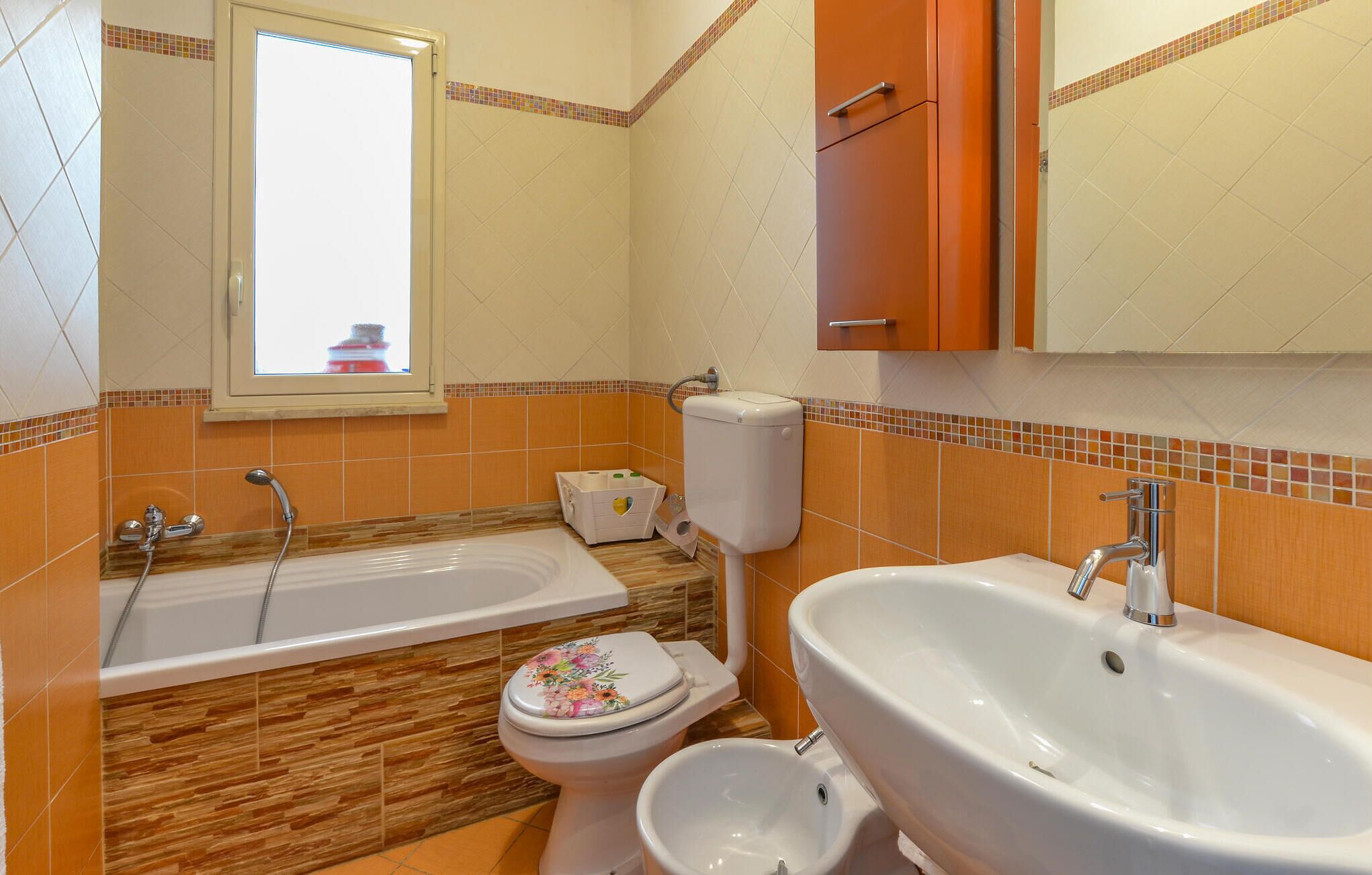 Une salle de bain équipée d’une baignoire, de toilettes, d’un bidet, d’un lavabo et d’une fenêtre.