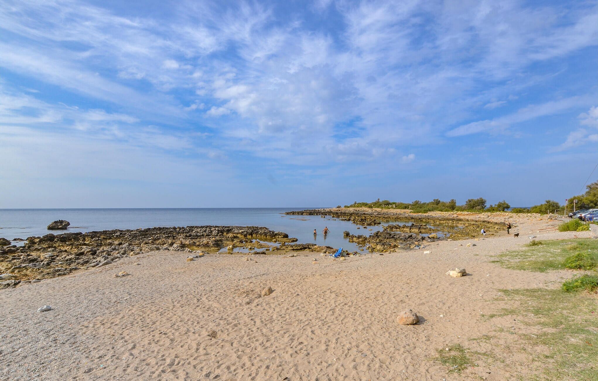 Ein Strand mit Felsformationen und ruhigem Wasser.